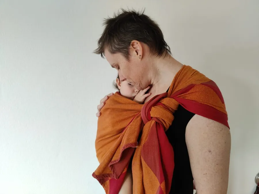 Liliane Fuchs portant un bébé en écharpe orange