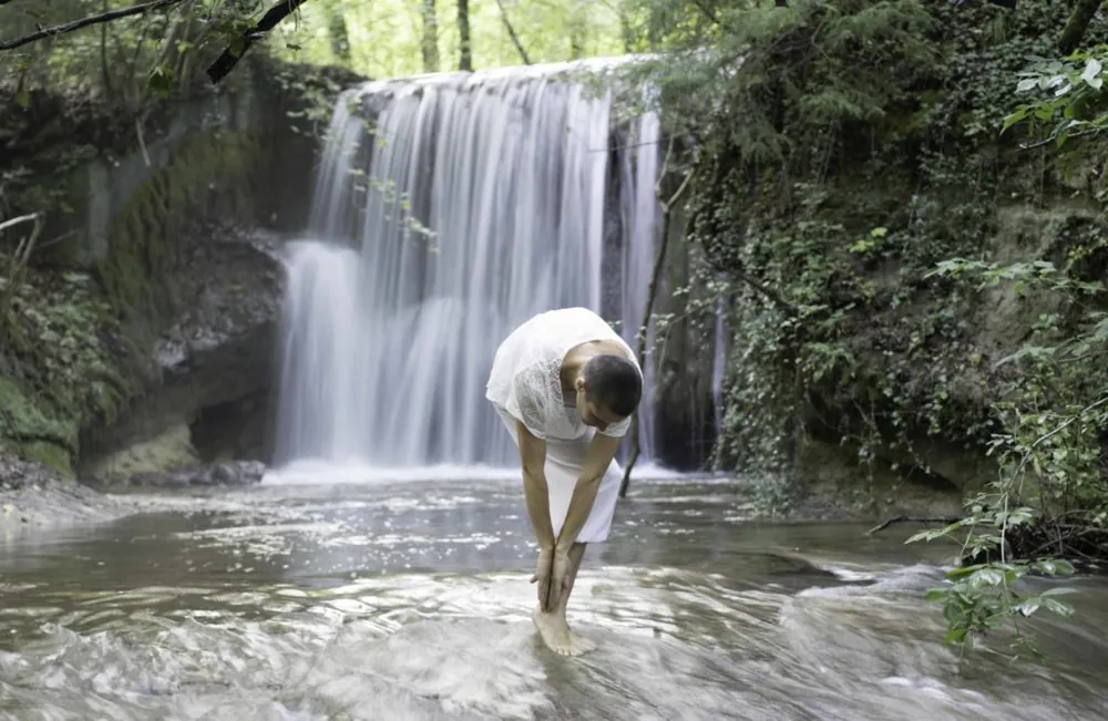 Pratique de la Téhima pieds dans l'eau devant une cascade
